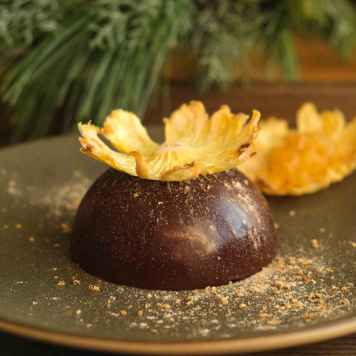 Gefüllte Schoko-Halbkugel mit Schokomousse und tropischer Ananas